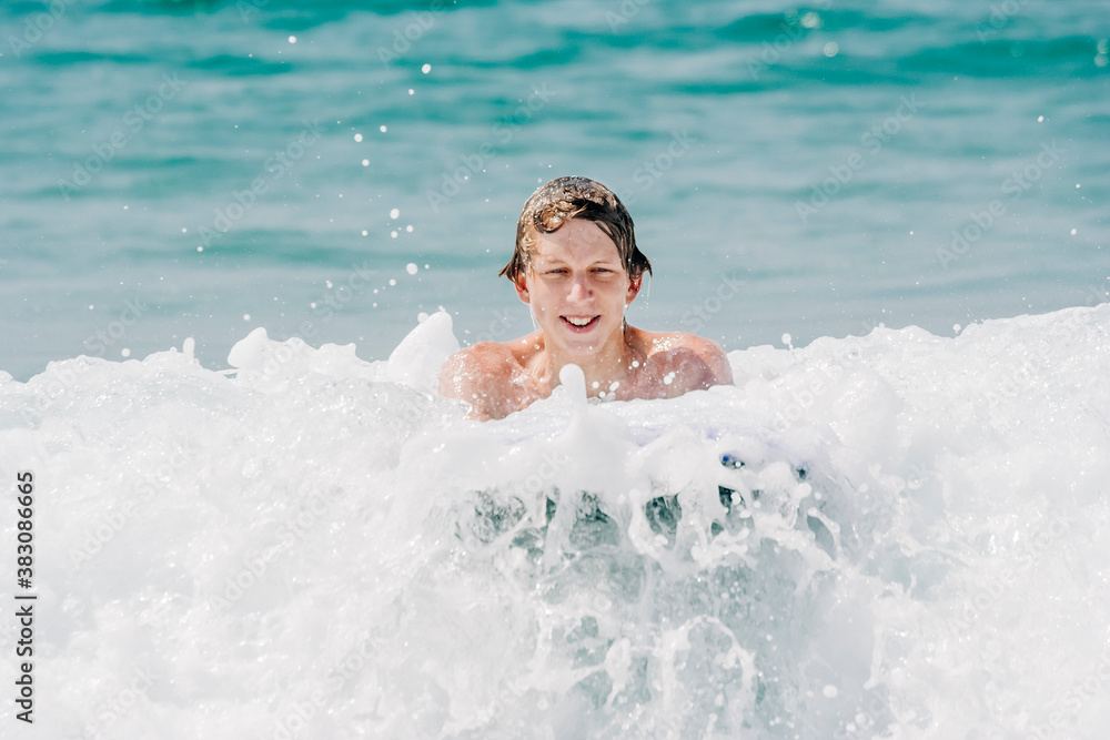 Teenage boy having fun with surfboard in waves of Atlantic Ocean Teenage boy having fun with surfboard in waves of Atlantic Ocean