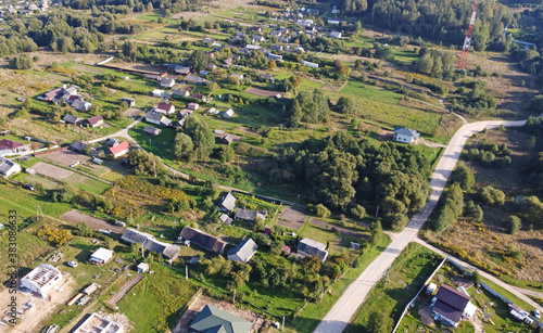 Beautiful top view of suburban cottages with park and forest. Rural landscape with roofs of small houses and villages