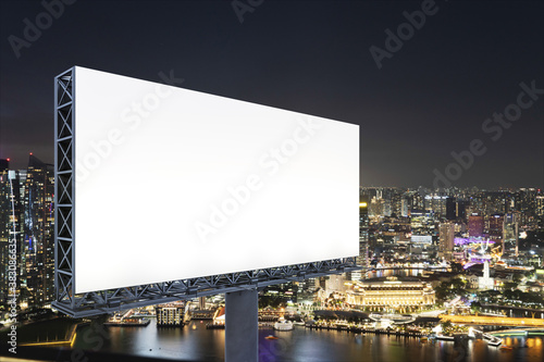 Blank white road billboard with Singapore cityscape background at night time. Street advertising poster, mock up, 3D rendering. Side view. The concept of marketing communication to sell idea.