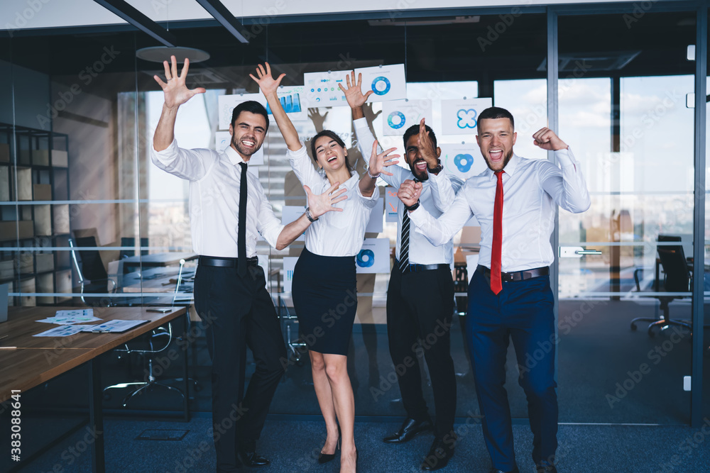 Group of accomplished male and female employees raising hands while celebrating completed business project, happy entrepreneurs satisfied with collaboration brainstorming in corporate office Group of accomplished male and female employees raising hands while celebrating completed business project, happy entrepreneurs satisfied with collaboration brainstorming in corporate office