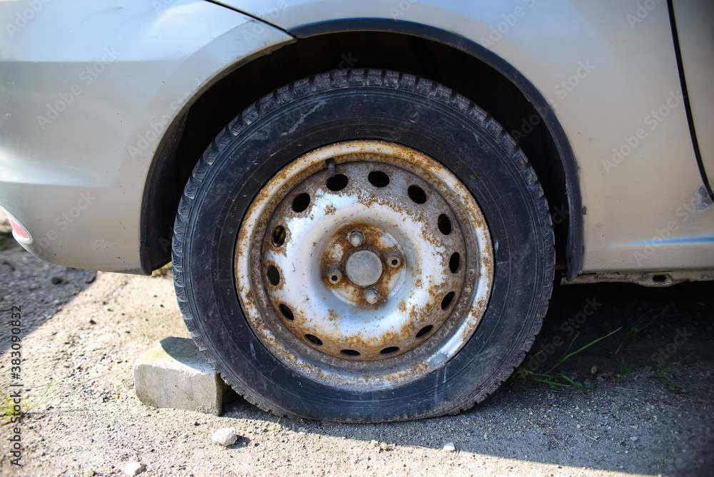 Flat tire, rusted car rim. Car on the street awaiting repair Flat tire, rusted car rim. Car on the street awaiting repair