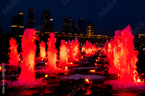 Evening and night views of the Moscow City skyscrapers through the glowing red fountains of Victory Park in Moscow. Lights of the night city.