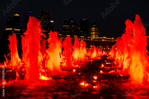 Evening and night views of the Moscow City skyscrapers through the glowing red fountains of Victory Park in Moscow. Lights of the night city.