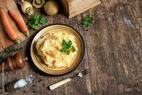 Schilderij op canvas Delicious and healthy mashed parsnips with potatoes and carrots and ingredients for making vegetarian parsnip puree on a dark wooden background