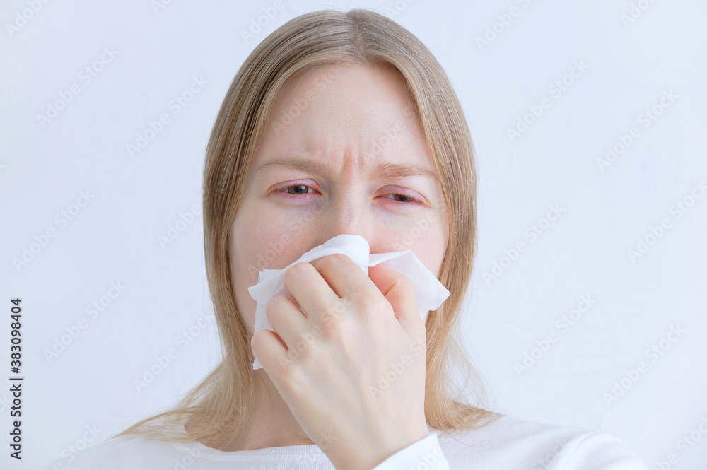 Colds and flu. Caucasian young woman sneezing into white napkin. Colds and flu. Caucasian young woman sneezing into white napkin.