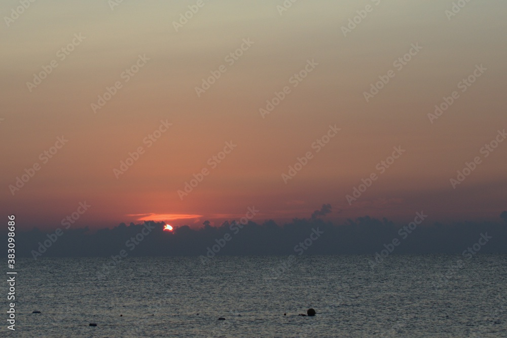 morning dawn. red rising sun over blurred horizon of sea and gray clouds