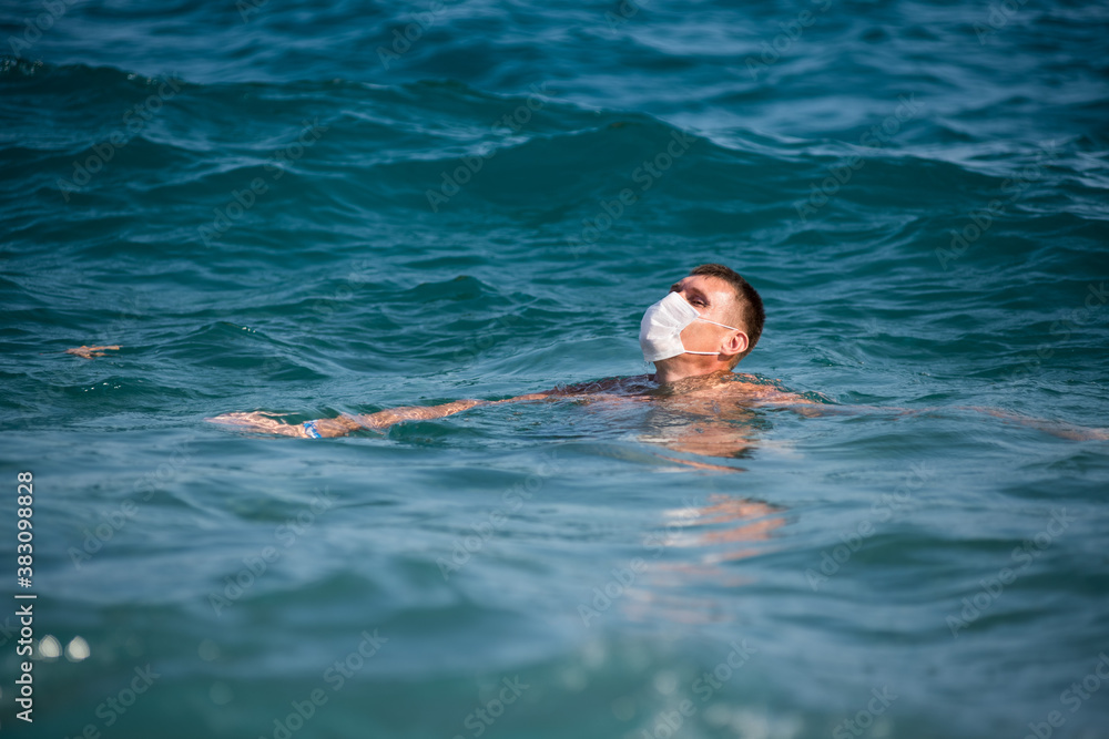 a man swims in the open sea wearing a mask during the covid 19 flu epidemic