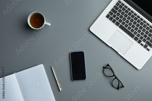 Above view flat lay of laptop and business accessories on grey workplace background, copy space