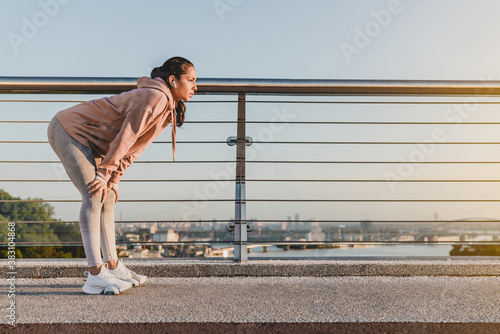Obraz na płótnie Young runner is having a break after jogging on the bridge.