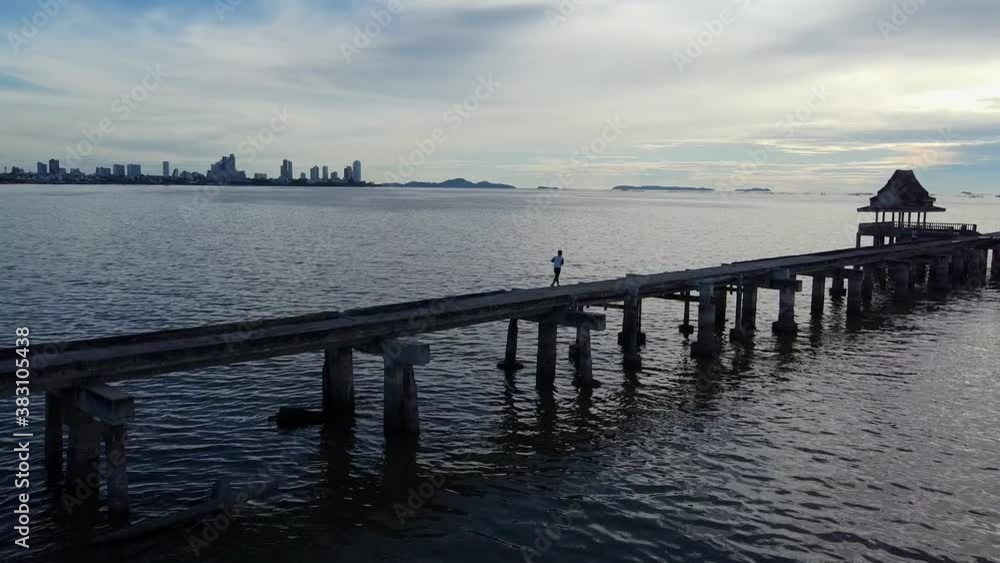 Thai local jogging on long temple pier late evening blue hour Thai local jogging on long temple pier late evening blue hour