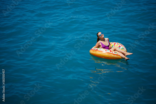 Carefree young girl woman enjoying a relaxing day at sea, floating on an inflatable ring, top view. Sea vacation concept © Дмитрий Ткачук