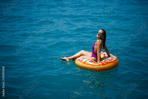 Carefree young girl woman enjoying a relaxing day at sea  floating on an inflatable ring  top view. Sea vacation concept