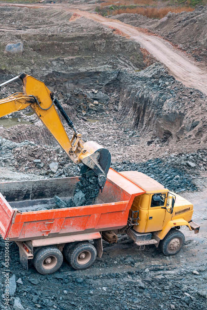 the process of loading soil with an excavator bucket into a truck at a construction site the process of loading soil with an excavator bucket into a truck at a construction site