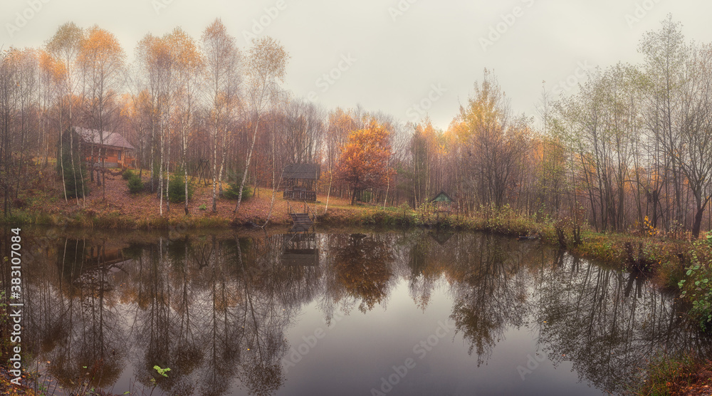 Misty late fall landscape, wild lake in the autumn forest with reflection in the calm water, scenic panoramic view