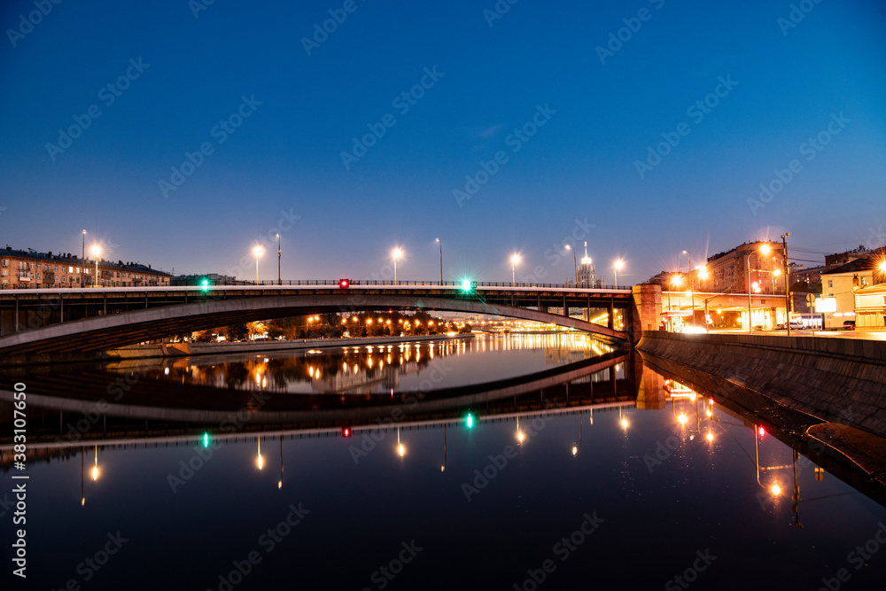 Fototapeta premium river embankment of a large metropolis at dawn with glowing lanterns reflections in the river