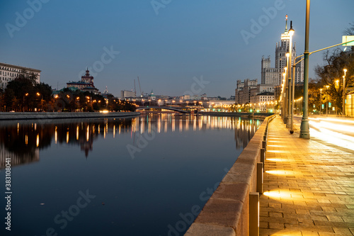 river embankment of a large metropolis at dawn with glowing lanterns reflections in the river