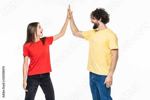 Portrait of a beautiful young couple standing and giving high five on the gray background
