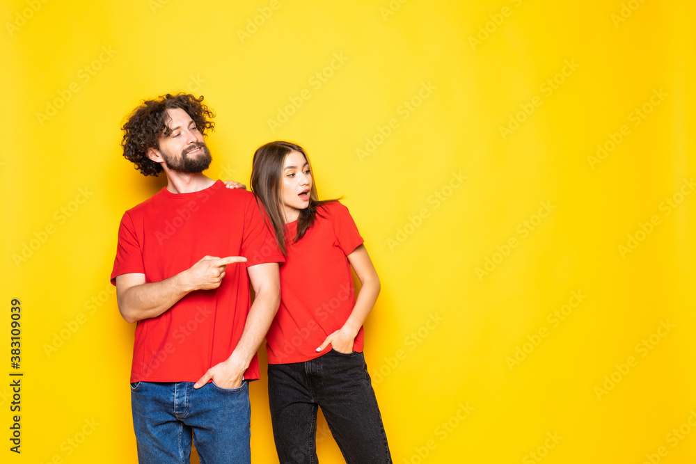 Obraz premium Young couple pointing to the side to present a product isolated on yellow background