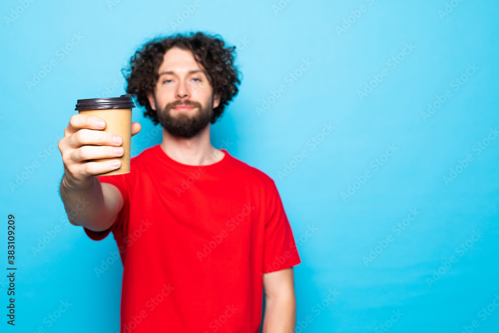 Portrait of a smiling young man pointed cup of coffee isolated on a blue background. Portrait of a smiling young man pointed cup of coffee isolated on a blue background.
