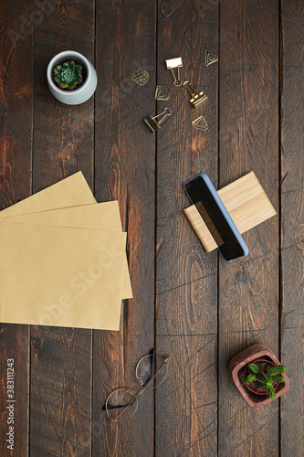 Minimal above view flat lay of business accessories craft paper, glasses and succulents over textured wooden workplace background, copy space