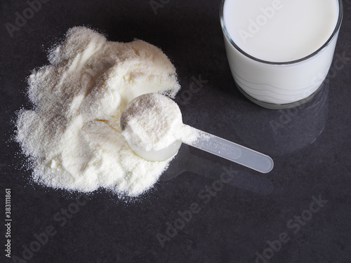 Protein powder, glucosamine in a plastic spoon for making a high-calorie drink, cocktail in a glass on a dark background, top view. Healthy sports nutrition for fitness photo