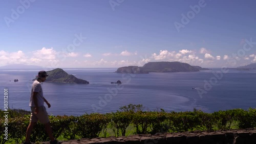 Male solo traveler looking out towards beautiful blue ocean and islands on clear and sunny day photo