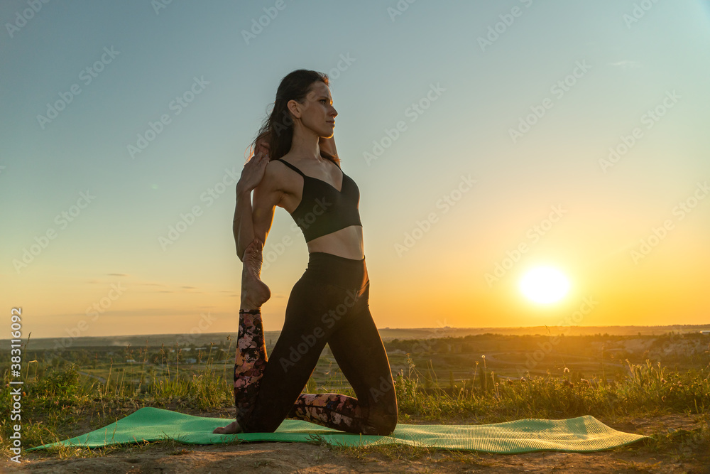 Young woman meditating in a yoga pose on nature at sunset. Concept of healthy lifestyle and relaxation