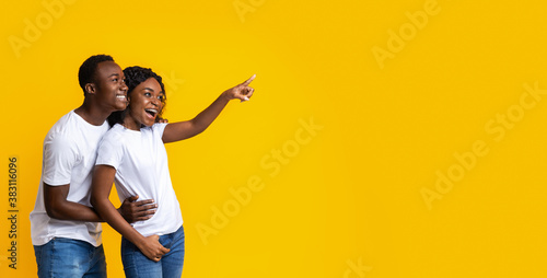 African-american man and woman pointing at empty space