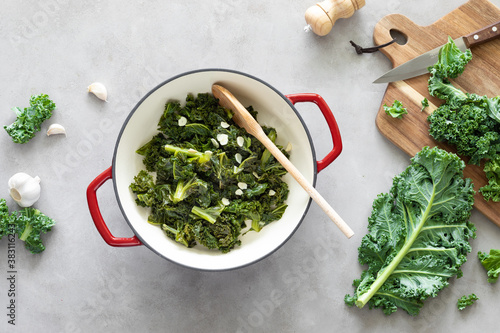 Canvas Print Sauteed kale with garlic in cast iron pan on kitchen table, healthy food concept