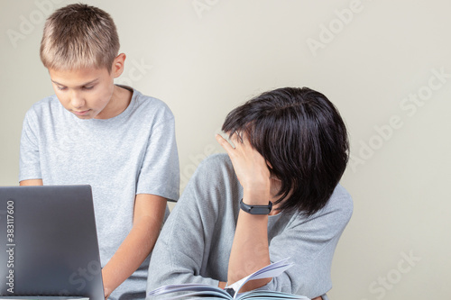Boy helping his mother use laptop computer to set up for online working, learning, video call at home