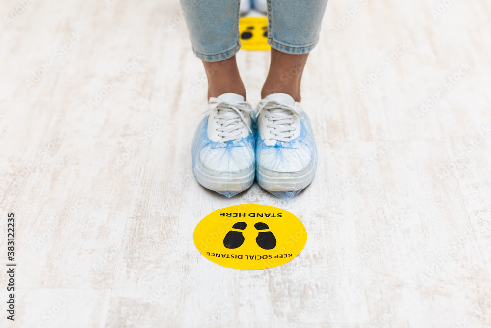 Female Feet Standing Near Social Distancing Warning Sign On Floor