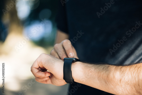 Close up view of male hand with modern smart watch gadget outside Black touchscreen. Checking notification online. Measuring distance, heart rate. Healthcare © uflypro