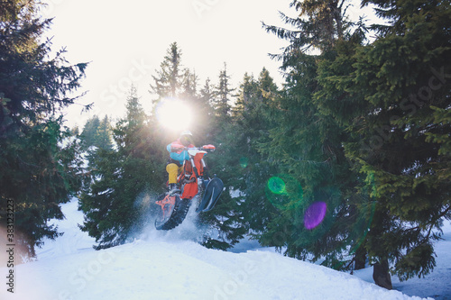 Snowbike rider in mountain valley in beautiful snow powder. Snowdirt bike with splashes and trail. Snowmobile winter sport riding photo