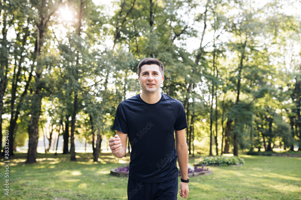 Adult man in sportswear jogging on the park in early morning. Sports people. Sportsman. Running activity. Healthy lifestyle Adult man in sportswear jogging on the park in early morning. Sports people. Sportsman. Running activity. Healthy lifestyle