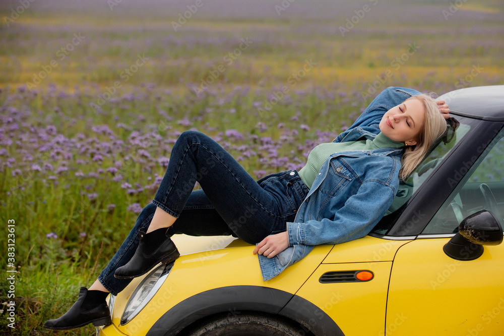 Style blonde with a car near flowers filed in autumn time Style blonde with a car near flowers filed in autumn time
