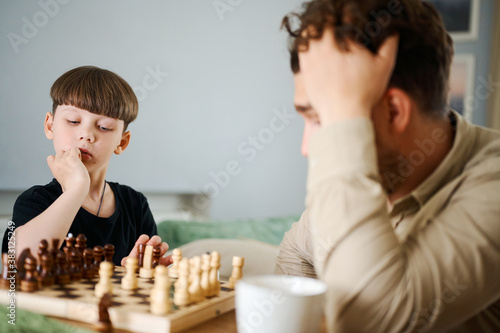 Father teaching son how to play chess. Concept of education and teaching.