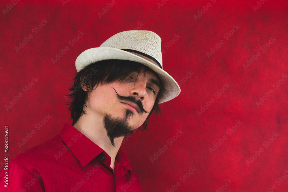 Male portrait. young man with hat in red shirt on the red background Male portrait. young man with hat in red shirt on the red background