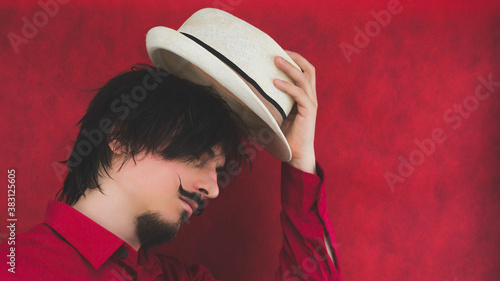 Male portrait. young man with hat in red shirt on the red background photo