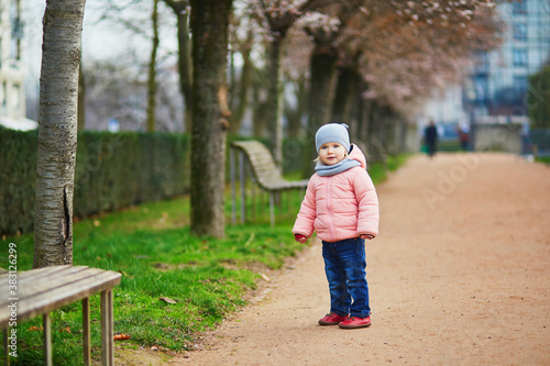 Adorable toddler girl walking in park on winter or spring day