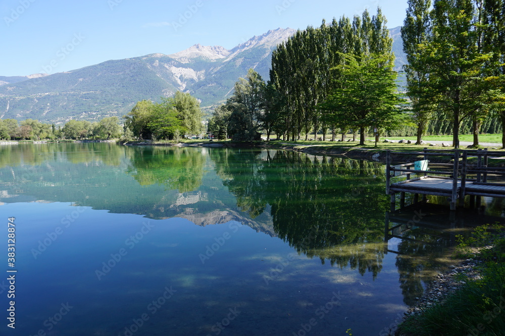 mirror reflection of trees and mountains in lake in the Alps, France