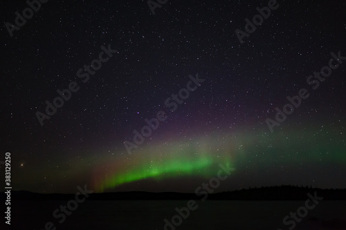 Panoramic view of the aurora borealis. Polar lights in the night starry sky over the lake. © lexuss