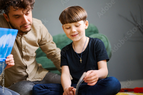 Young caucasian father spending time at home with sons and reading books on the floor. Happy parent playing with preshool children. Home education concept photo