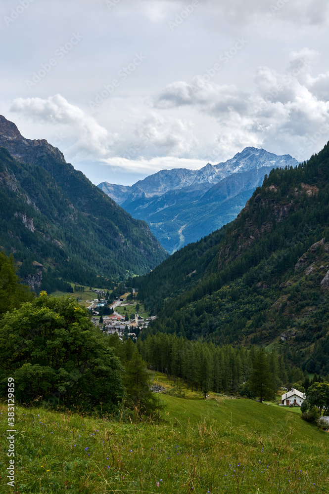 a beautiful mountain valley with a village at the bottom of the valley against the backdrop of high mountains and a cloudy sky