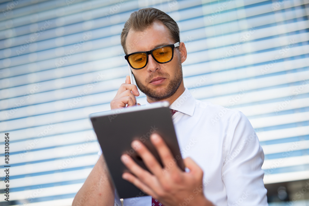 Businessman using a tablet while talking on the phone Businessman using a tablet while talking on the phone