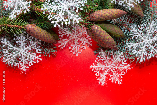 Happy New year and merry Christmas. Christmas red background with fir trees, cones and snowflakes.