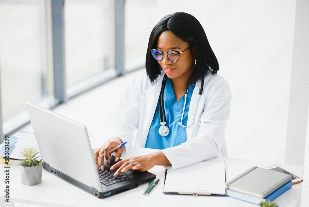 Young African-American doctor working on laptop in clinic Young African-American doctor working on laptop in clinic