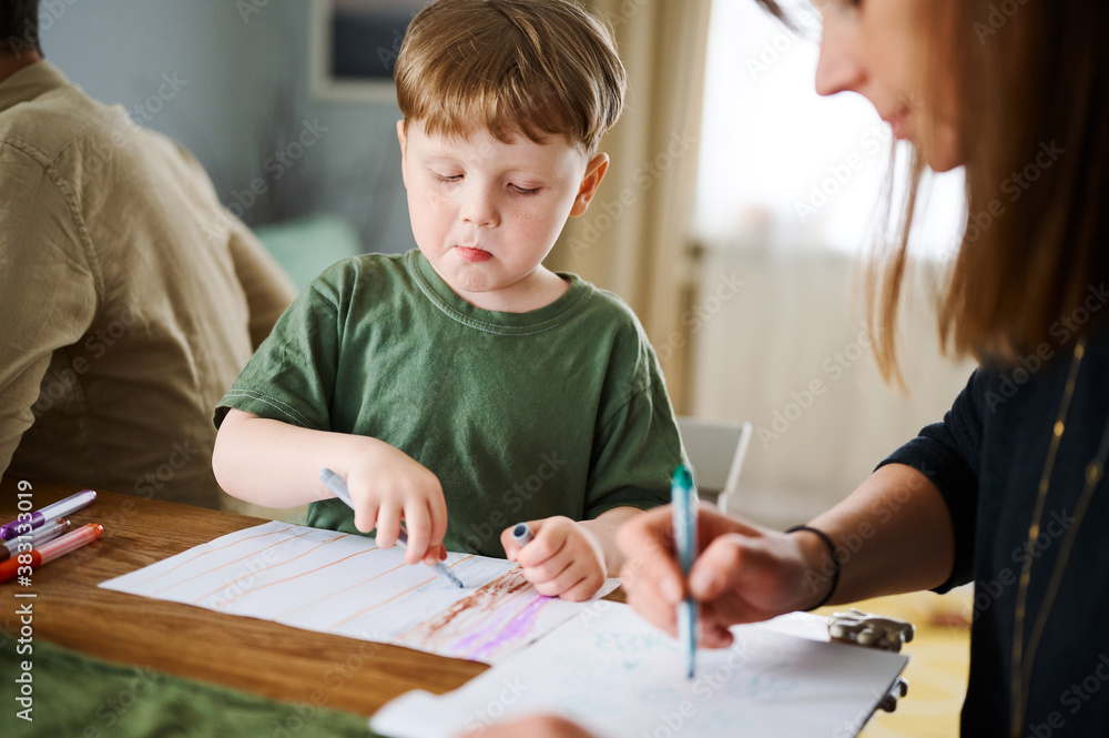 Happy family. Mother with little son painting and drawing together. Caucasian boy with his mother studying at home Happy family. Mother with little son painting and drawing together. Caucasian boy with his mother studying at home