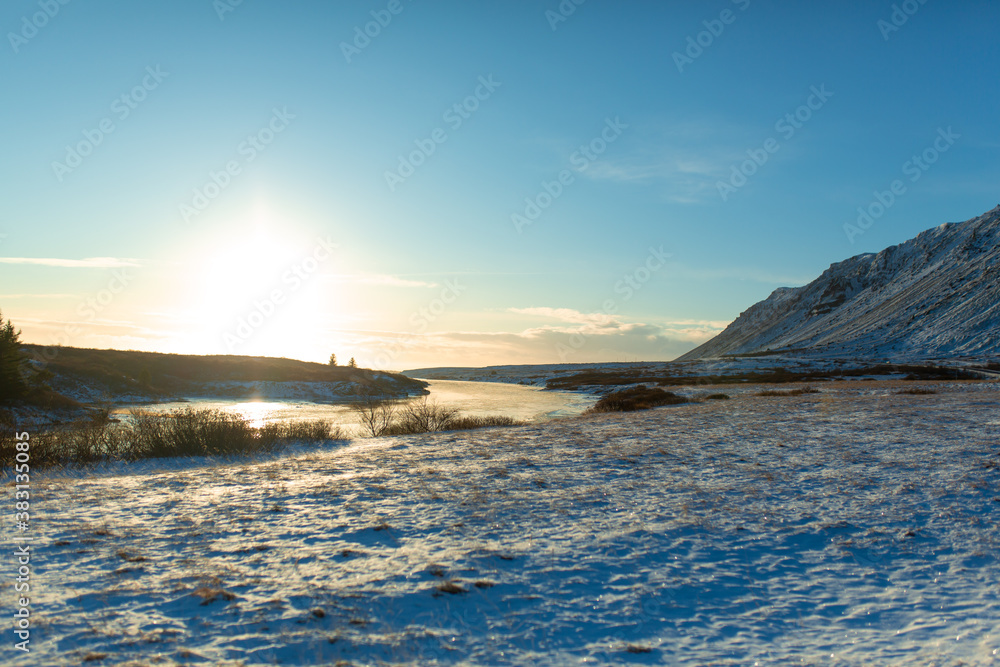 River on the plain in Iceland. The banks are covered with snow. Winter landscape, open spaces.