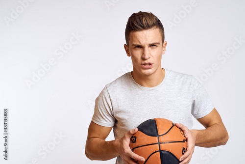 happy man with ball in hand and in white t-shirt on light background gesturing with hands cropped view
