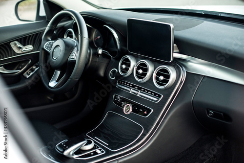 Modern car interior, black perforated leather, aluminum, details controls, leather steering wheel